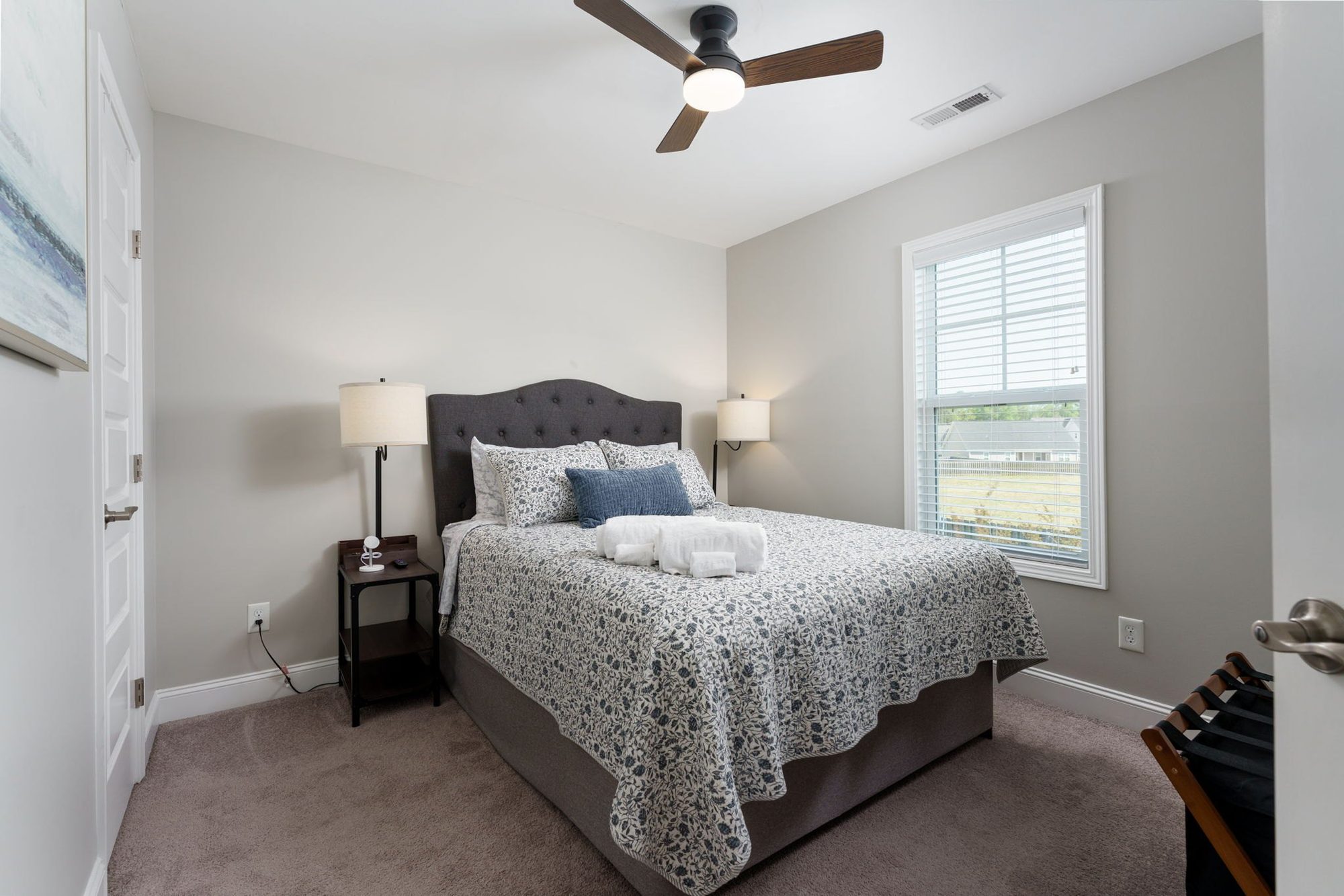Queen bedroom with patterned blue-and-white bedding and upholstered headboard